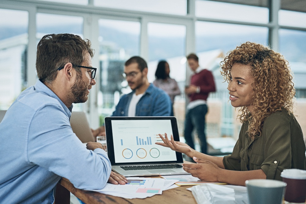 Two business people review healthcare analytics on a computer.