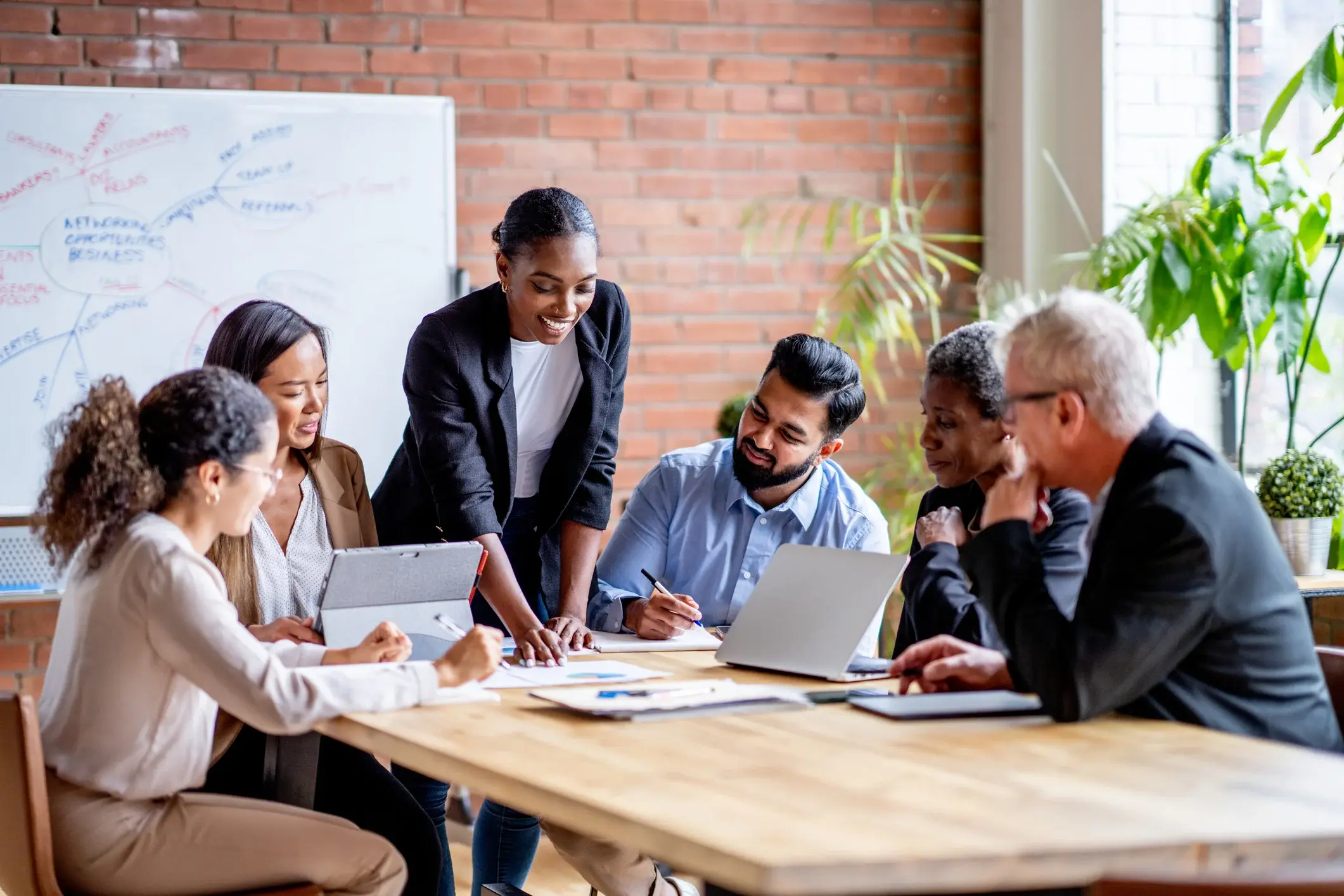 A group of employees review data on a laptop in an office. 